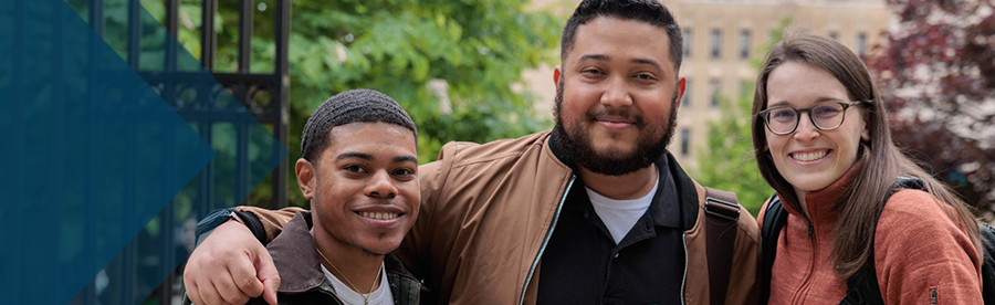 Three student embrace while smiling for the camera