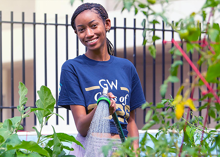 student watering plants in the grow garden